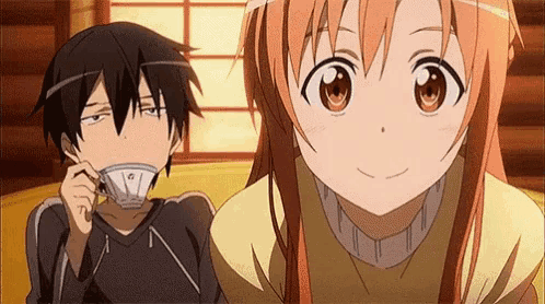 a boy and a girl are sitting next to each other and the girl is holding a cup of tea .