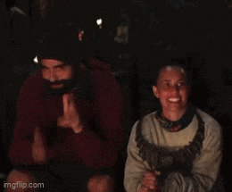 a man with a beard is sitting next to another man with his finger on his mouth
