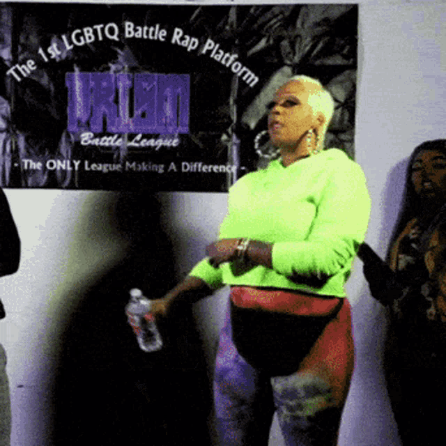 a woman in a neon green sweatshirt stands in front of a sign that says the 1st lgbtq battle rap platform