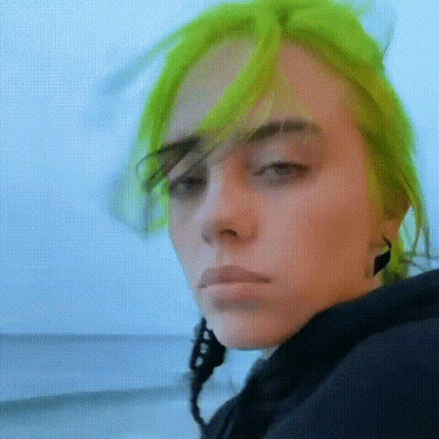 a close up of a person 's face with green hair and a black jacket .