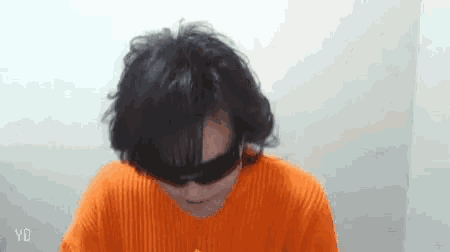 a person wearing sunglasses and an orange sweater with the letters yd on the bottom