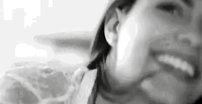 a black and white photo of a woman smiling and looking at the camera .