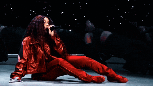 a woman in a red jacket is singing into a microphone on a stage