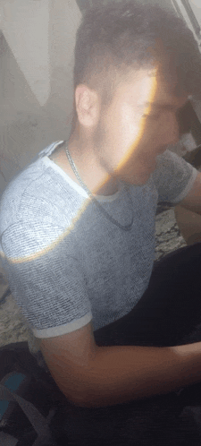 a man with a necklace around his neck is sitting down