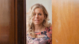 a woman in a floral dress is peeking through a door