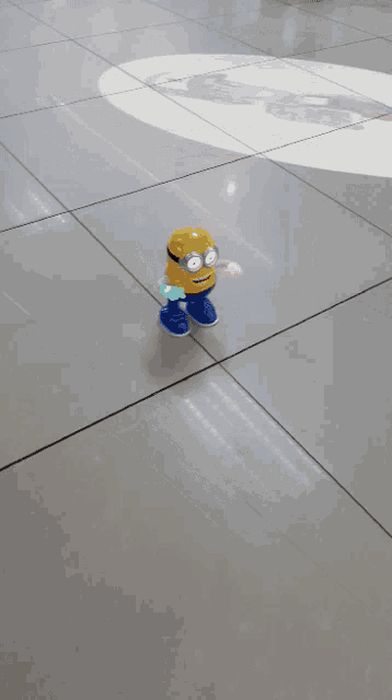 a yellow and blue toy minion is on a tiled floor