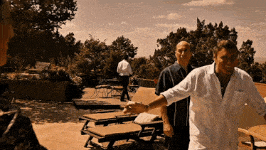 a man in a white shirt shakes hands with another man in a black shirt
