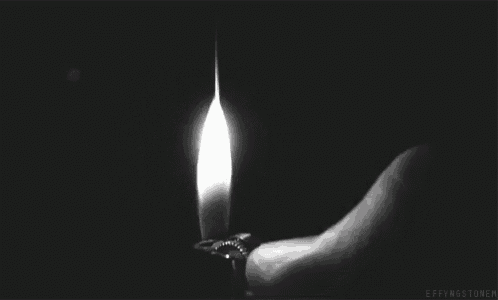 a black and white photo of a person lighting a light bulb .