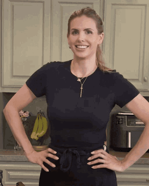 a woman wearing a black shirt and a gold cross necklace smiles for the camera