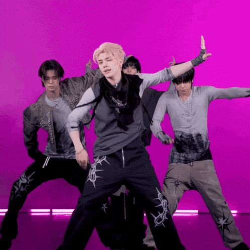 a group of young men are dancing in front of a purple backdrop