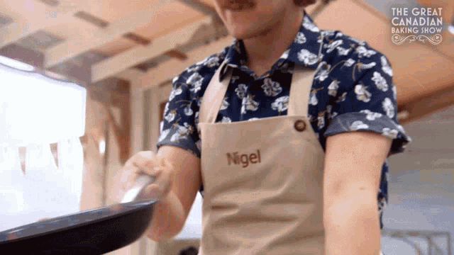 a man wearing an apron with nigel embroidered on it