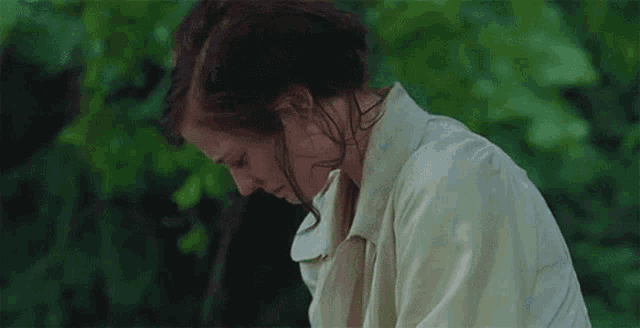 a woman in a white coat is sitting in front of a forest .