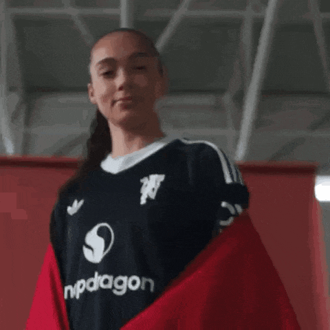 a woman wearing a black adidas jersey is standing in a gym .