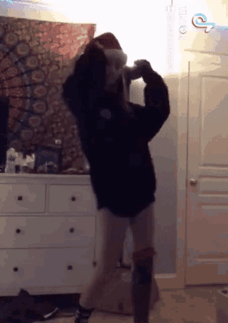 a girl wearing a santa hat is dancing in a room