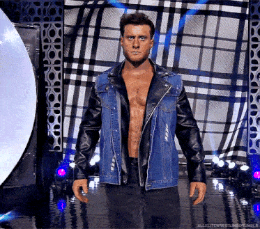 a man in a denim jacket and leather sleeves is standing in front of a checkered wall ..