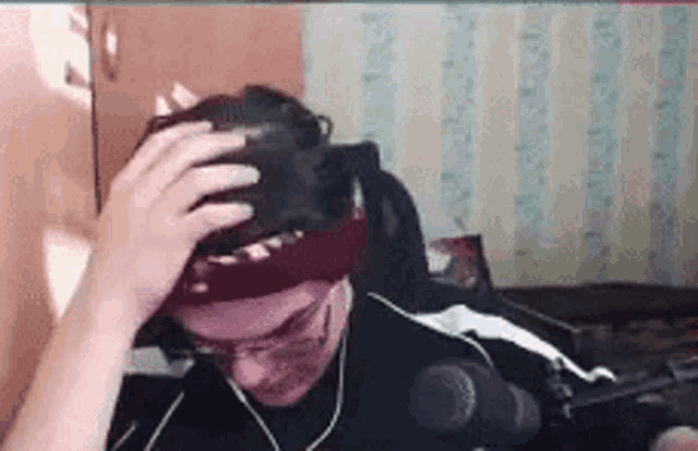 a man wearing a headset is sitting in front of a microphone in a room .