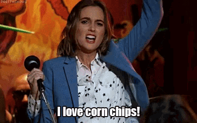 a woman in a blue suit is singing into a microphone and says " i love corn chips "