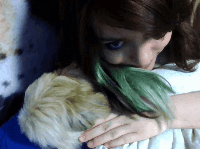 a woman with green hair is hugging a small white dog