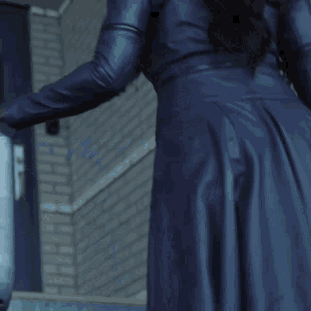 a woman in a blue leather coat is leaning on a metal railing
