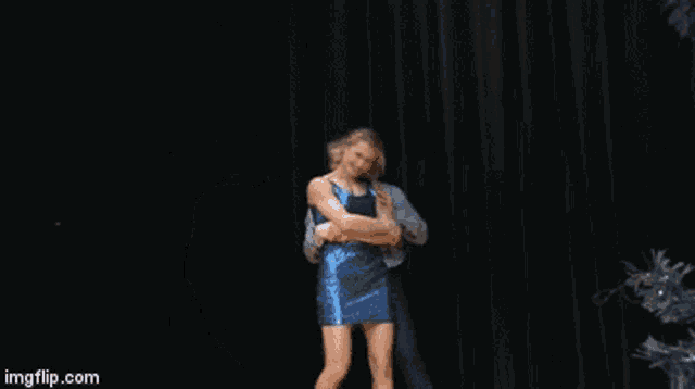 a woman in a blue dress is dancing with a man in a suit