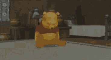 a winnie the pooh teddy bear is sitting on the floor in a room