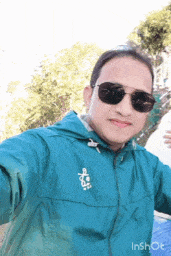 a man wearing sunglasses and a green jacket takes a picture