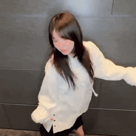 a young girl in a white shirt is dancing in front of a wall .