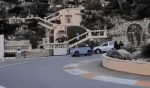 a car is driving down a street next to a building and stairs .