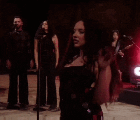 a woman is singing into a microphone in front of a band
