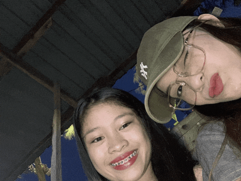 two girls are posing for a picture and one is wearing a hat with ny on it