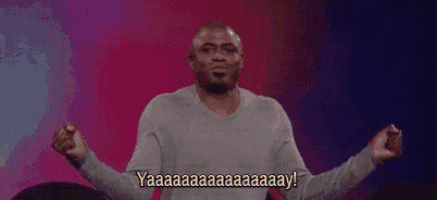 a man is sitting on a stage with his arms outstretched and saying yaaa .
