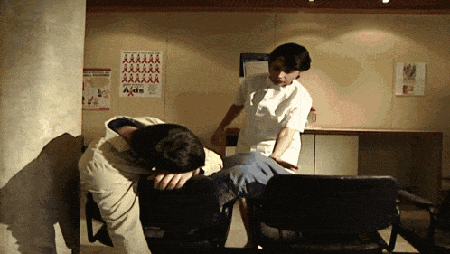 a nurse stands next to a man in a waiting room with aids posters on the walls