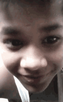 a close up of a young boy 's face looking at the camera .