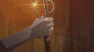 a close up of a person 's hand holding a sword in front of a sunset .