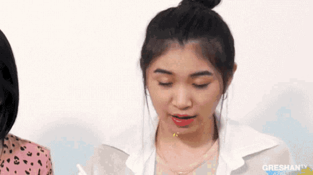 a woman with her eyes closed and her hair in a bun is looking at something .