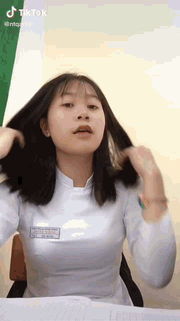 a girl in a white shirt has a name tag on her chest that says " thanh thanh "