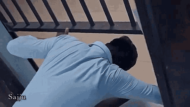 a man in a blue shirt is laying on the floor in front of a railing with the name saiju on the bottom