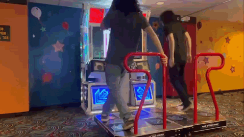 two people are dancing on a dance machine in a room with a sign that says " no open tea " on it