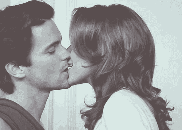 a man and a woman are kissing in front of a wall