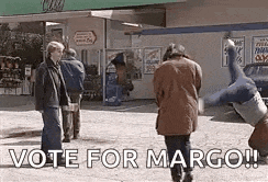 a man is doing a handstand in front of a gas station and a sign that says vote for margo .