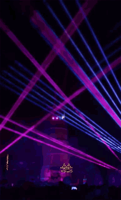 a crowd of people watching a concert with purple lights coming out of the ceiling