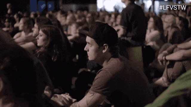 a man is sitting in the middle of a crowd of people watching a movie .