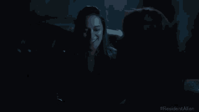 two women are smiling in a dark room with # residentalien written on the bottom