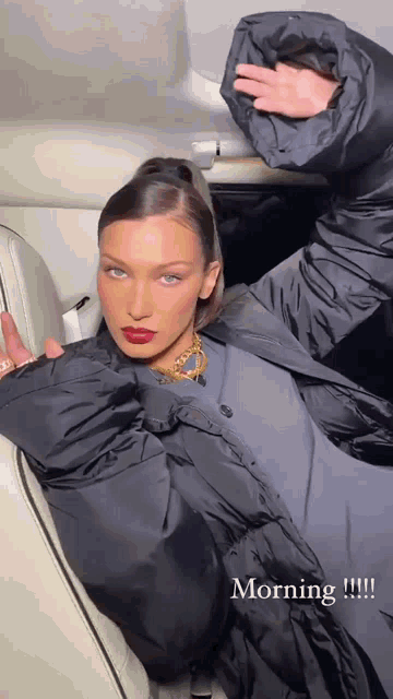 a woman in a black jacket is sitting in the back seat of a car