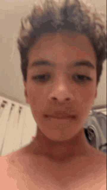 a young boy without a shirt is making a funny face in a bathroom .