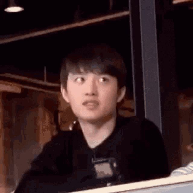 a young man is smiling while sitting at a table in front of a window in a restaurant .