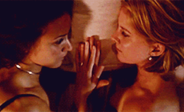 two women are touching each other 's faces and one has a ring on her finger
