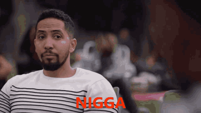 a man wearing a striped shirt with the word nigga written on it