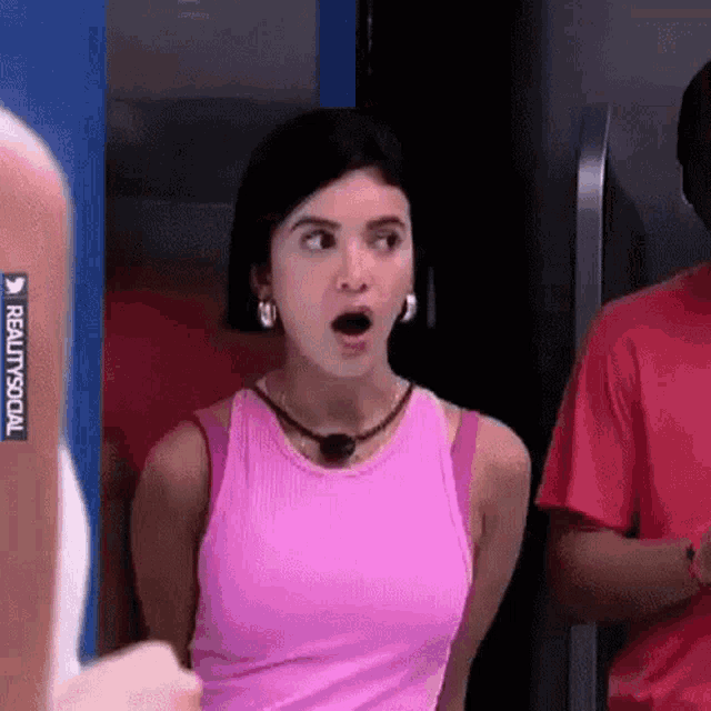 a woman in a pink tank top is standing in front of a man in a red shirt .