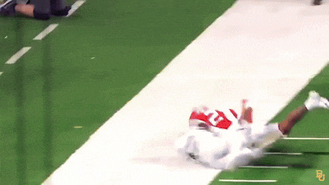 a football player is laying on his back on the field with the letter b on the side of his jersey